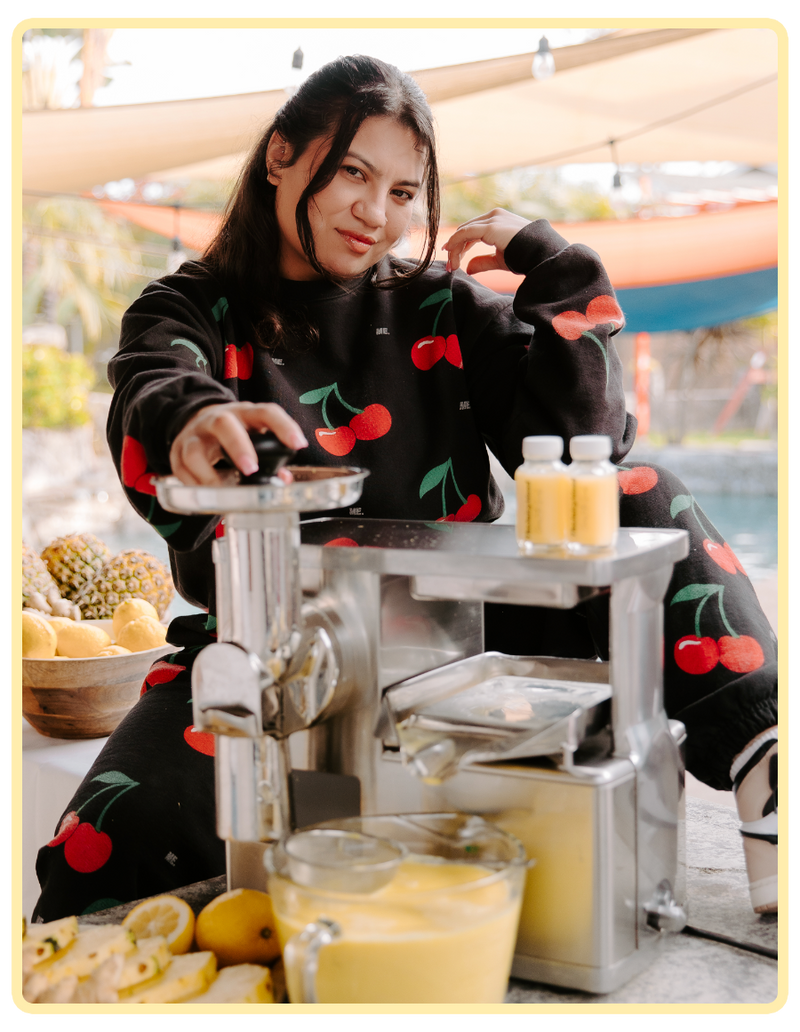 Person using a juicer with fruits and a cherry-themed outfit in an outdoor setting